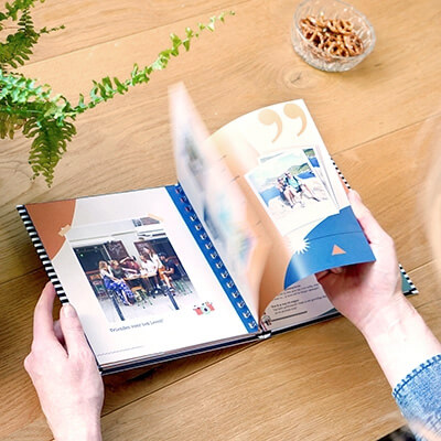 Een vriendenboek met fotopagina's als afscheidscadeau doorbladeren aan tafel